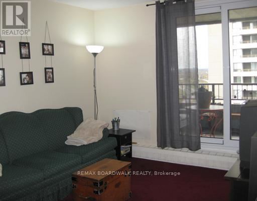 A living room with a green couch, a lamp, and pictures on the wall.