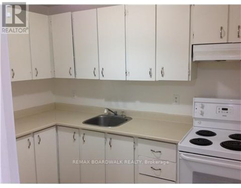 A kitchen with white cabinets and a white stove top oven.