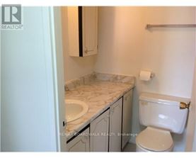 A bathroom with a toilet, sink, and cabinet.