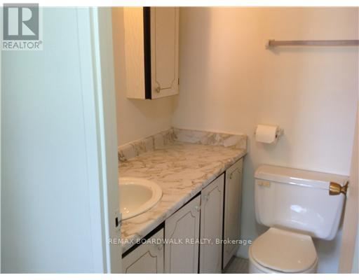 A bathroom with a toilet, sink, and cabinet.
