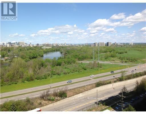 A highway with cars driving on it and a city skyline in the distance.