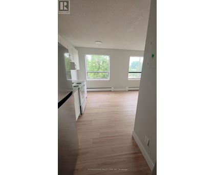 A kitchen with white cabinets and a wooden floor.