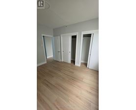 A room with white walls and wooden flooring with three doors.