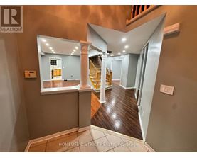 A hallway with a wooden floor and a staircase with a yellow railing.