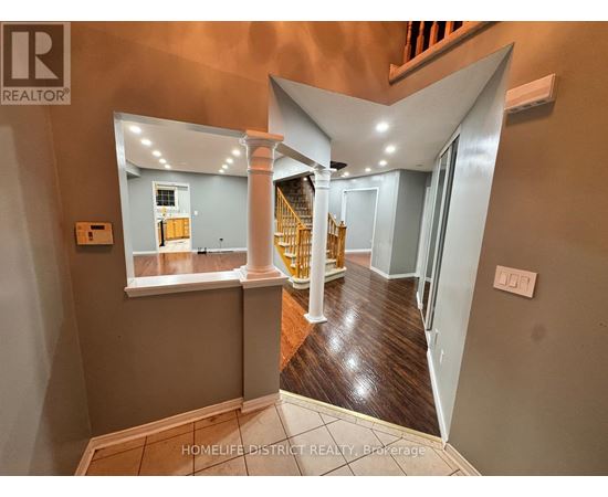 A hallway with a wooden floor and a staircase with a yellow railing.