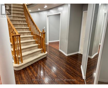 A staircase with wooden handrails and a beige carpeted runner leads to a landing with a white door.