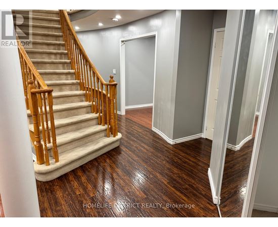 A staircase with wooden handrails and a beige carpeted runner leads to a landing with a white door.