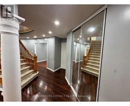 A spacious hallway with a wooden floor and a staircase with a wooden railing.