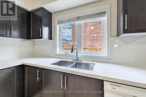A kitchen with dark brown cabinets and a stainless steel sink.