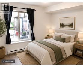 A bedroom with a large bed and a window with black curtains.