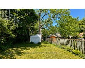 A white shed sits in a grassy yard.