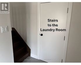 A white door with a sign that says "Stairs to the Laundry Room".