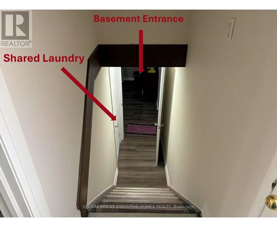 A stairway leading to a basement entrance with a shared laundry area.