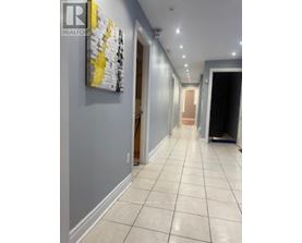 A hallway with a painting on the wall and a door at the end.