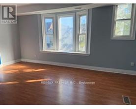 A room with a large window and wooden flooring.