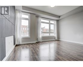 A spacious room with wooden floors and large windows.