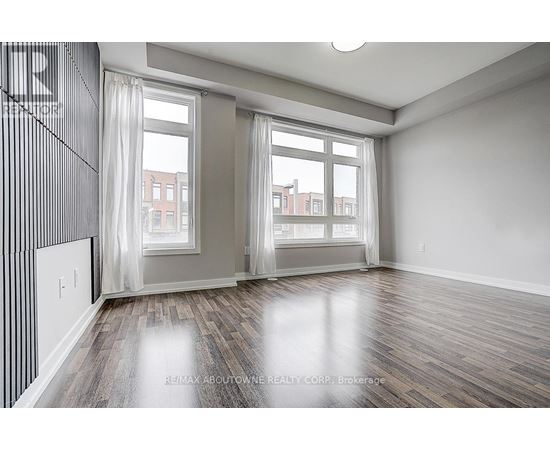 A spacious room with wooden floors and large windows.