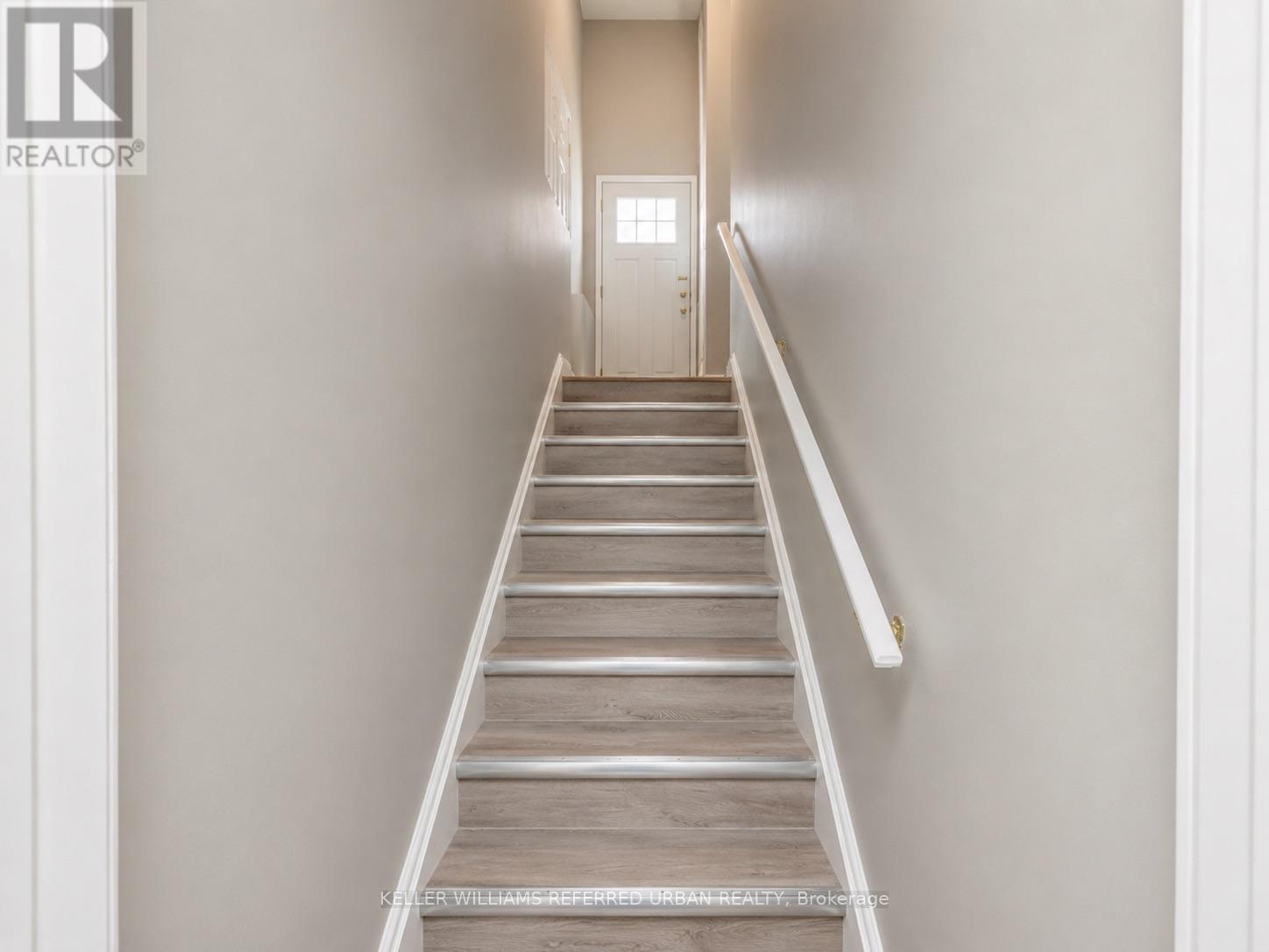 A staircase with a white railing leads to a door at the end.