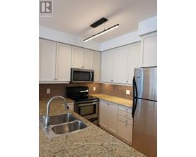 A kitchen with a stainless steel refrigerator, sink, and cabinets.