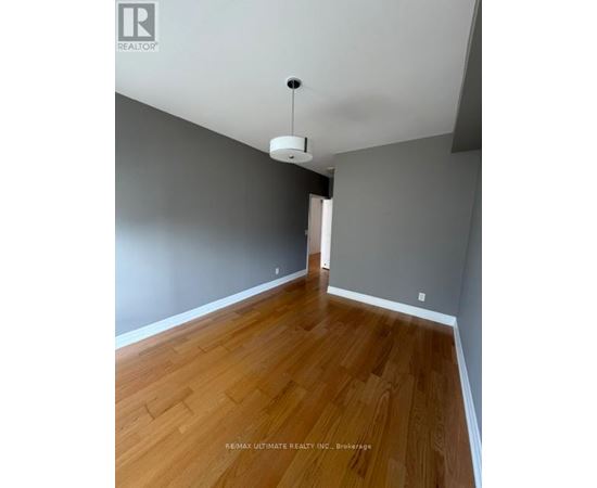 A room with wooden flooring and a ceiling light.