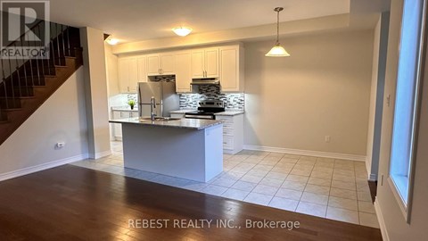 A kitchen with a staircase on the left side and a counter on the right side.