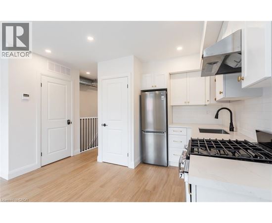 A modern kitchen with white cabinets and a stainless steel refrigerator.