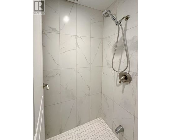 A shower with a marble tile wall and a white tile floor.