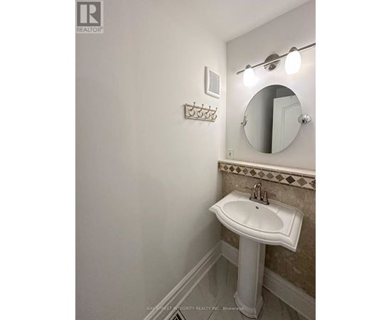 A white pedestal sink in a bathroom with a mirror and lights above it.