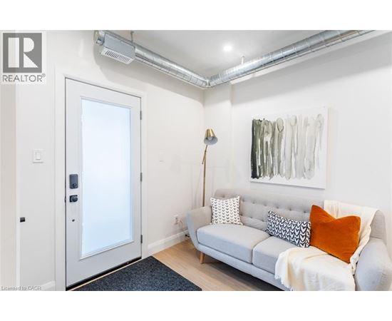 A living room with a grey couch and a painting on the wall.