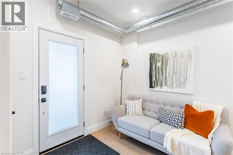 A living room with a grey couch and a painting on the wall.
