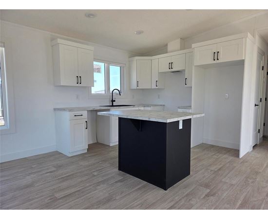 A kitchen with a black island and white cabinets.
