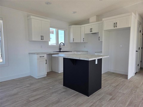 A kitchen with a black island and white cabinets.