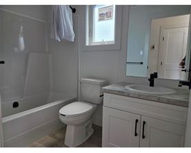 A white toilet in a bathroom with a white cabinet and a white sink.
