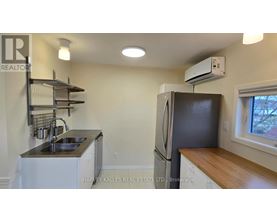 A kitchen with a sink, refrigerator, and a window.