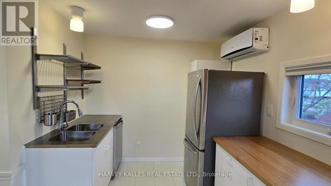 A kitchen with a sink, refrigerator, and a window.