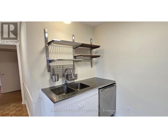 A stainless steel kitchen sink with a shelf above it.