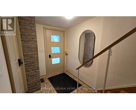 A hallway with a brick wall and a wooden staircase.