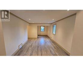 A spacious room with wooden flooring and a window.