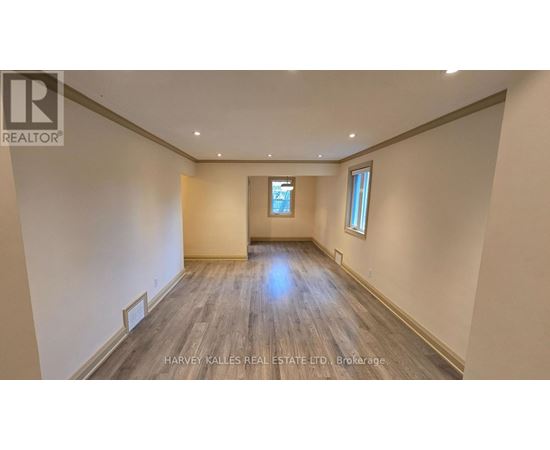 A spacious room with wooden flooring and a window.