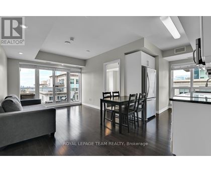 A well-lit, spacious living room with a grey sofa and a dining table set for four.