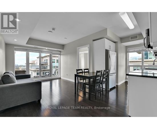 A well-lit, spacious living room with a grey sofa and a dining table set for four.
