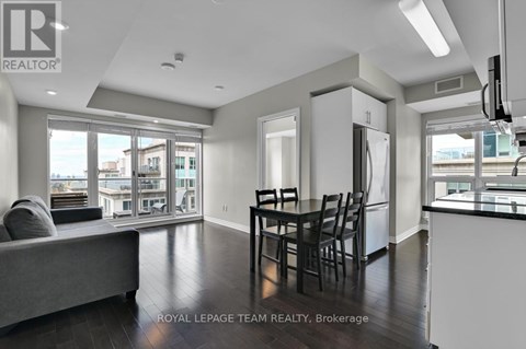 A well-lit, spacious living room with a grey sofa and a dining table set for four.