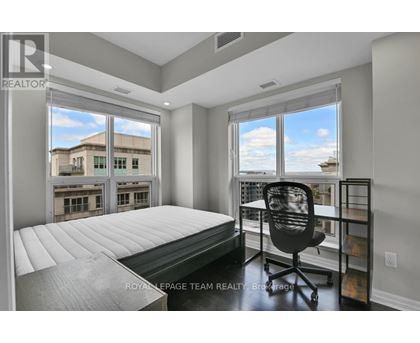 A bedroom with a large bed and a chair in front of a window.