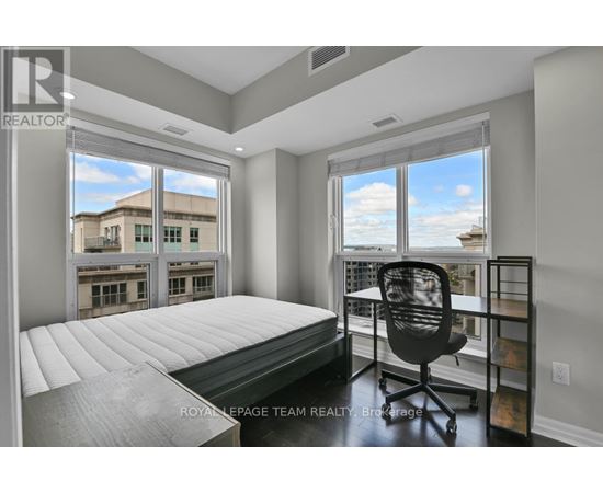 A bedroom with a large bed and a chair in front of a window.