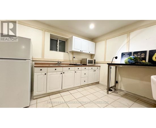 A kitchen with white cabinets and a white fridge.