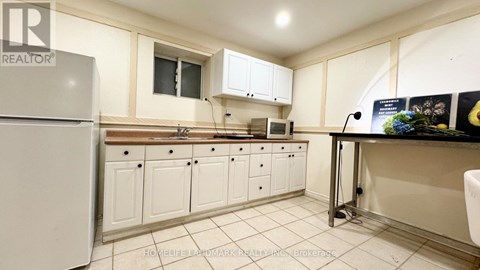 A kitchen with white cabinets and a white fridge.