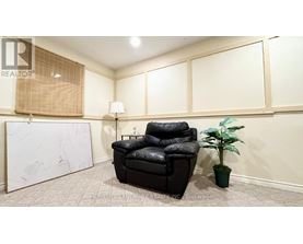 A black leather chair sits in a room with a white wall and a plant.
