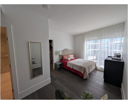 A bedroom with a bed, nightstand, and a plant.
