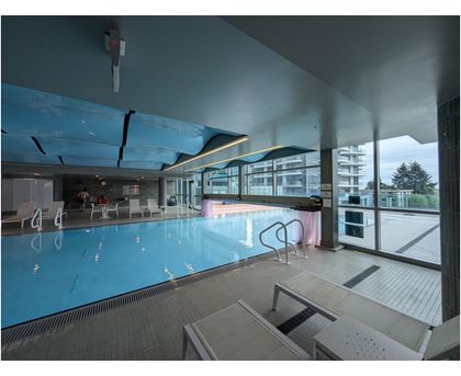 A large indoor swimming pool with a glass wall on one side.