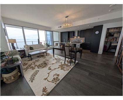 A living room with a rug on the floor and a dining table with chairs.